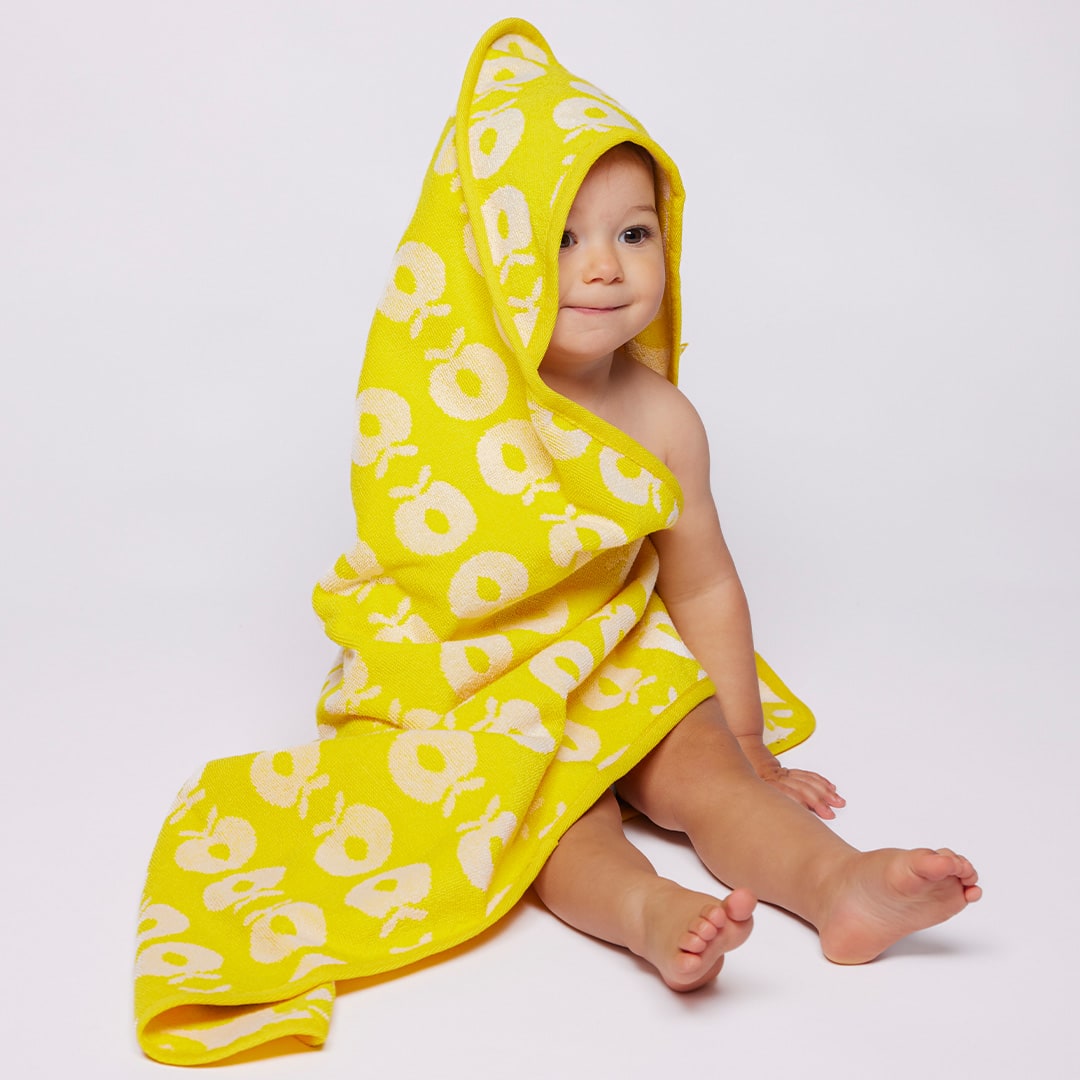 Child wrapped in a yellow hooded towel with a pattern on a white background
